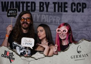 Three friends pose with fun props at a Wanted by the CCP City Paper photo booth.