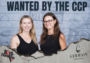 Two women in black outfits smiling at the Wanted by the CCP Best of Charleston photo booth.