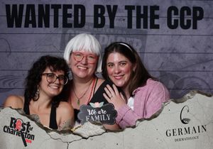 Three women pose with a We Are Family sign at Best of Charleston CCP photo booth.