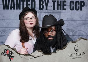 Two people in hats pose at Best of Charleston Wanted by the CCP photo booth with Germain Dermatology.