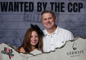 Smiling couple poses at Best of Charleston Wanted by the CCP photo booth sponsored by Germain Dermatology.