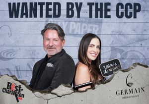 Couple poses at Best of Charleston CCP wanted poster photo booth sponsored by Germain Dermatology.