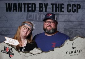 Couple poses at Wanted by the CCP City Paper Best of Charleston photo booth sponsored by Germain Dermatology.