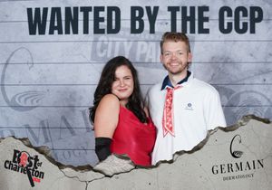 Smiling couple poses at Best of Charleston Wanted by the CCP photo booth with Germain Dermatology sponsor.