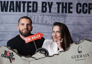 Couple posing at Best of Charleston CCP photo booth, man holding The Killer sign.