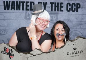 Two women posing with fun props at Wanted by the CCP Best of Charleston photo booth.
