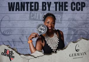 Woman smiling at Wanted by the CCP Best of Charleston photo booth holding a Lets Party sign.