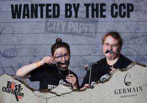 Two people holding novelty mustache props at the Wanted by the CCP Best of Charleston event.