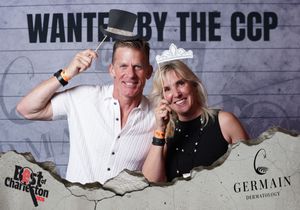 Two people pose playfully with prop accessories at a Best of Charleston event sponsored by Germain Dermatology.