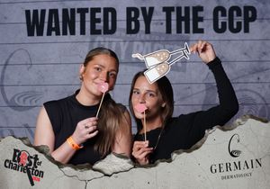 Two women posing with cocktail props at the Wanted by the CCP Best of Charleston photo booth.