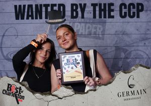 Two women pose with Best of Charleston award plaque at CCP wanted photo booth event.