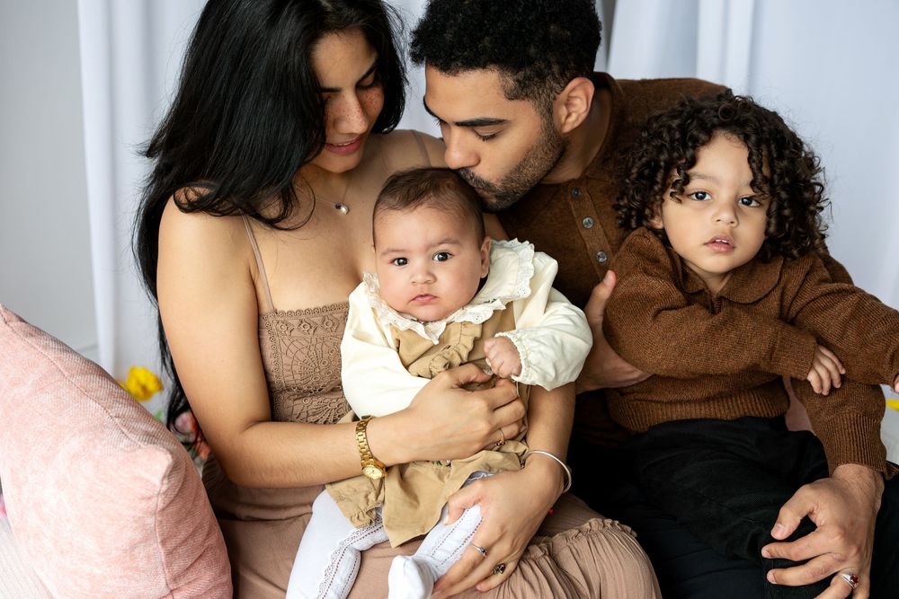 Parents tenderly hold their two young children in an intimate family portrait.