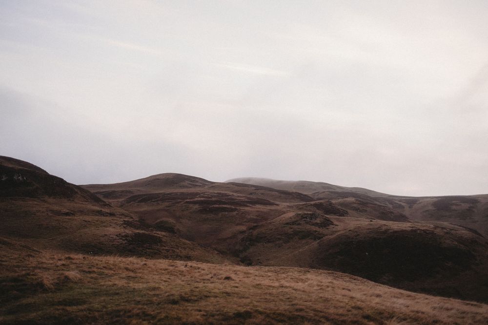 Rolling brown hills under a moody overcast sky in a remote highland landscape.