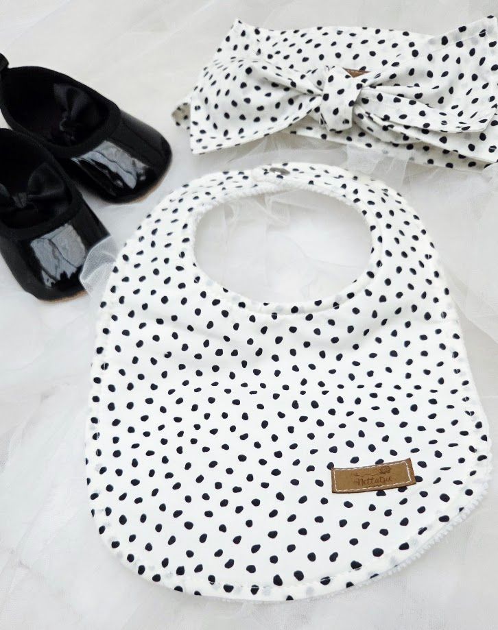Gray floral baby bib set with pacifier clip and burp cloth, featuring bow print fabric and leather label accents.