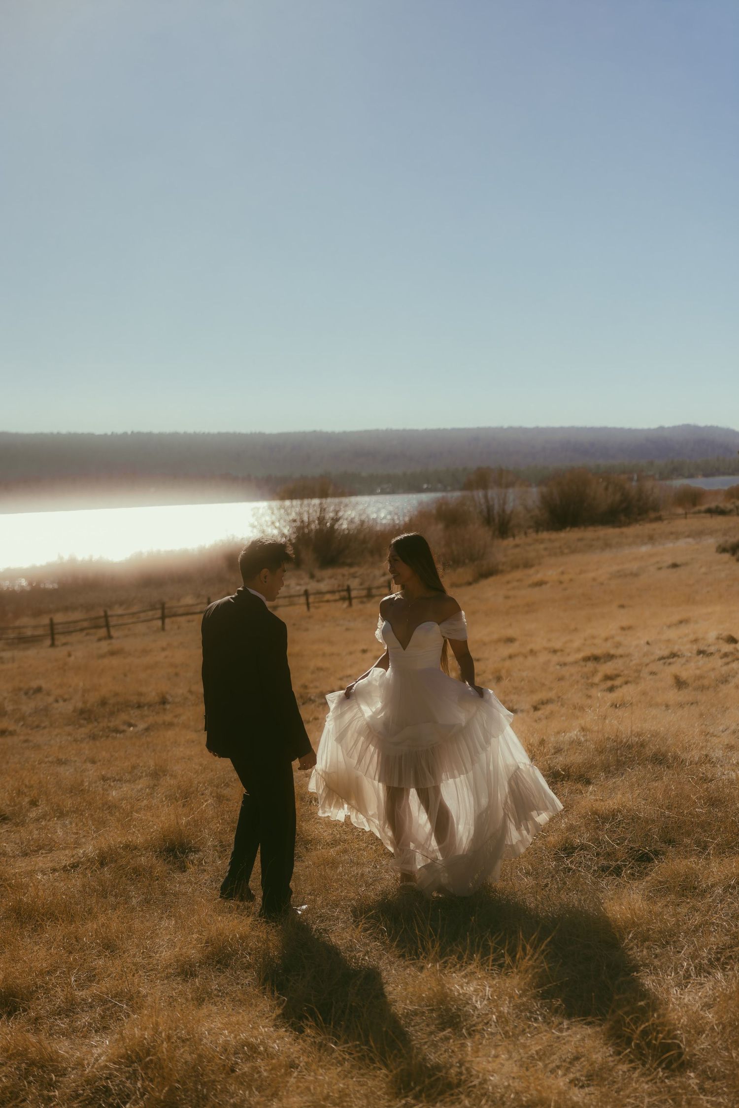 Bride and groom embrace beneath a sheer veil against a pine tree, golden hour light streaming through a Los Angeles forest wedding.