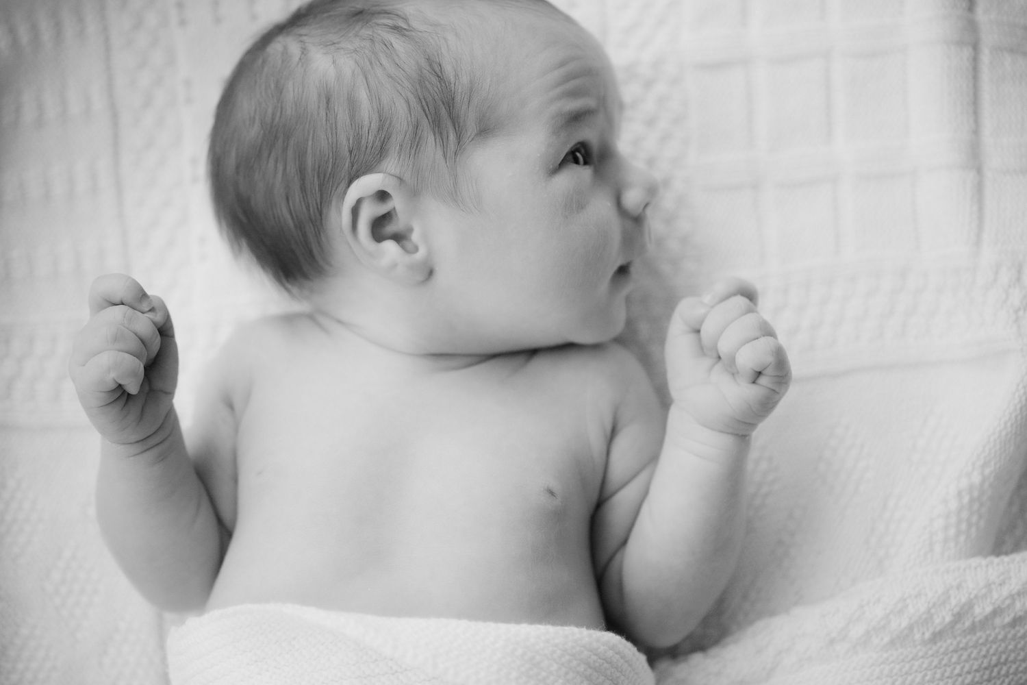 Black and white photo of alert newborn baby looking up at mother during newborn session Vancouver