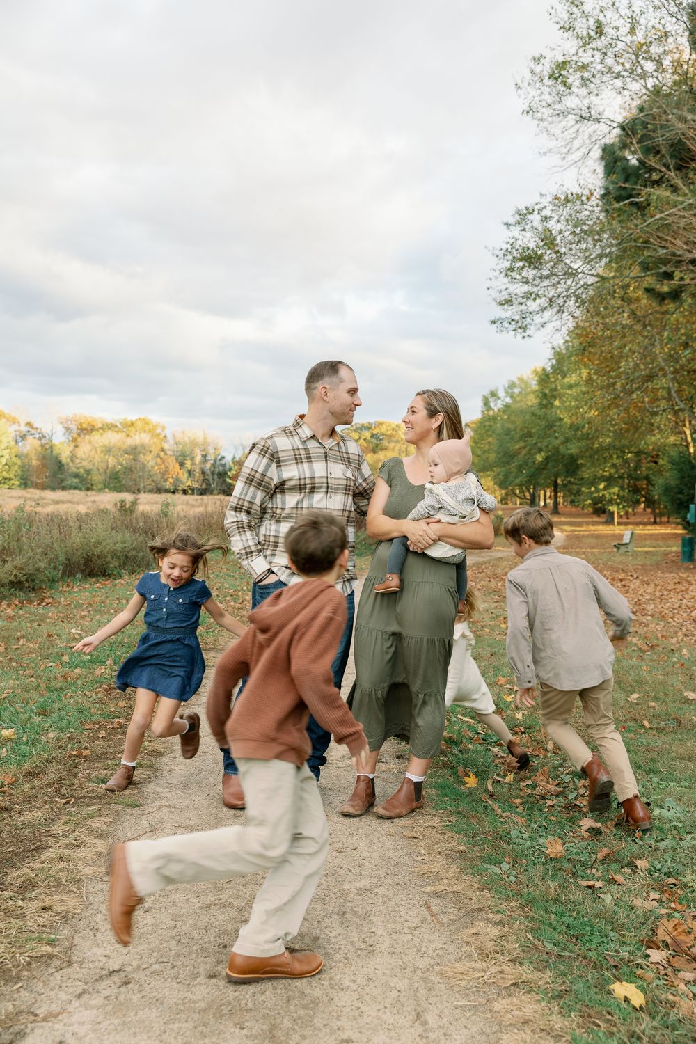 Family of six enjoying an autumn walk on a dirt path surrounded by fall foliage.