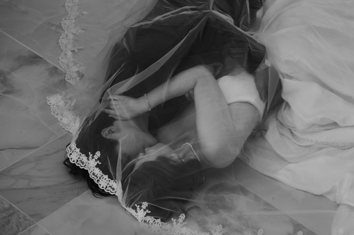 Romantic wedding portrait of bride and groom kissing under the veil.