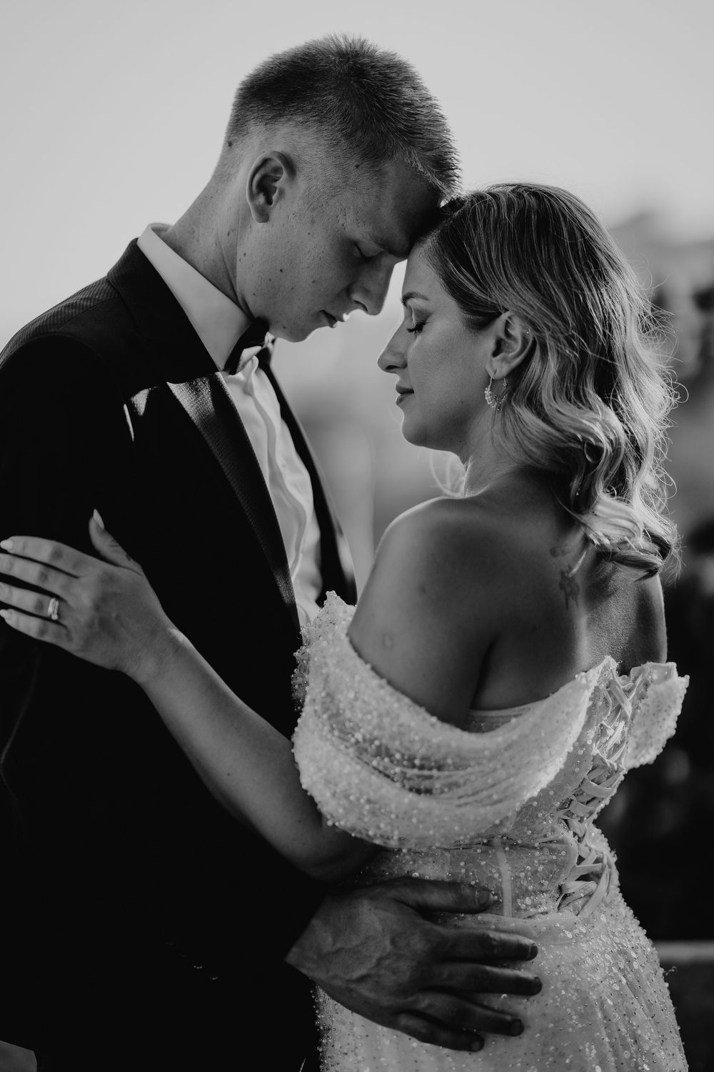 Intimate black and white portrait of bride and groom touching foreheads in a tender romantic moment.