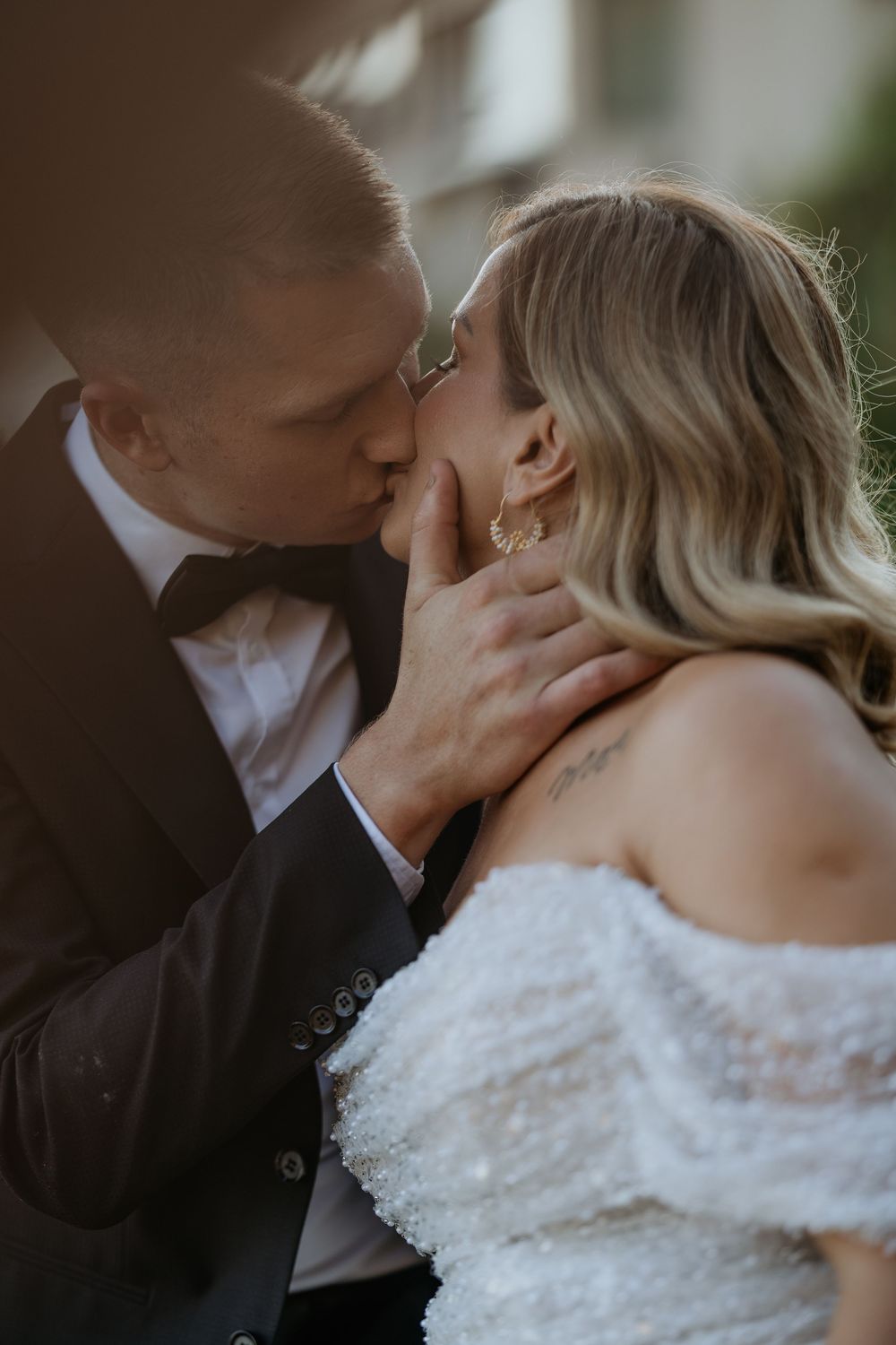 Bride and groom share a passionate kiss during outdoor wedding photo session.