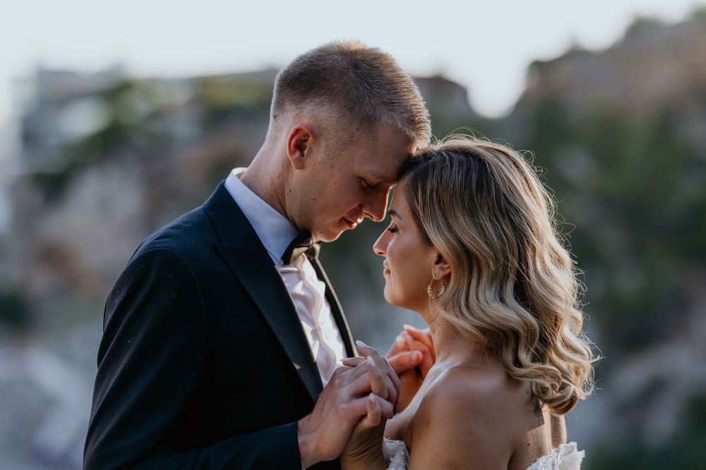 Bride and groom share an intimate forehead touch moment during wedding portraits.
