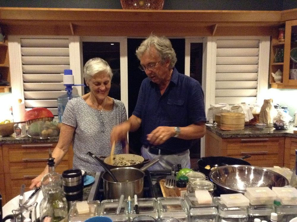 Elderly couple cooking together in a cozy kitchen, preparing a meal with pots and pans on the stovetop.