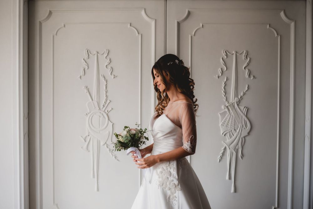 Elegant white room with decorative wall moldings and natural light creating a bridal preparation space.