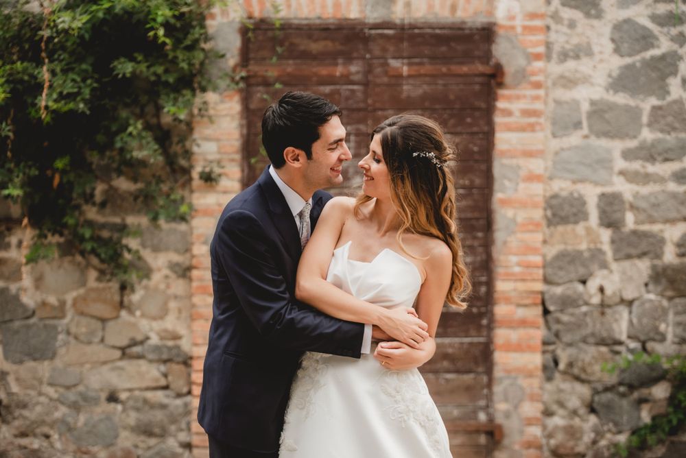 Romantic wedding portraits against rustic stone wall backdrop.