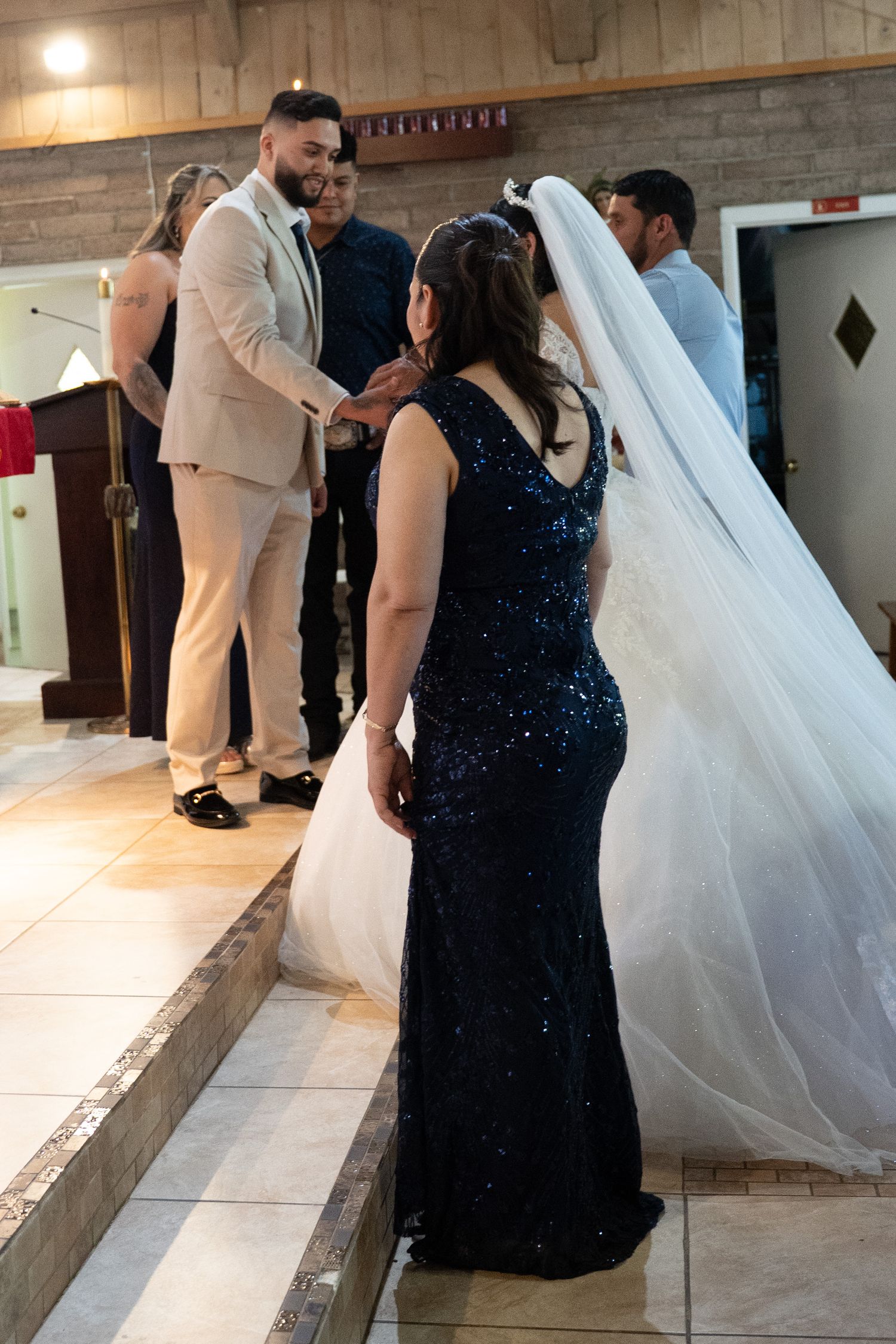 Bride and groom exchanging vows at church altar during wedding ceremony with guests in elegant attire.