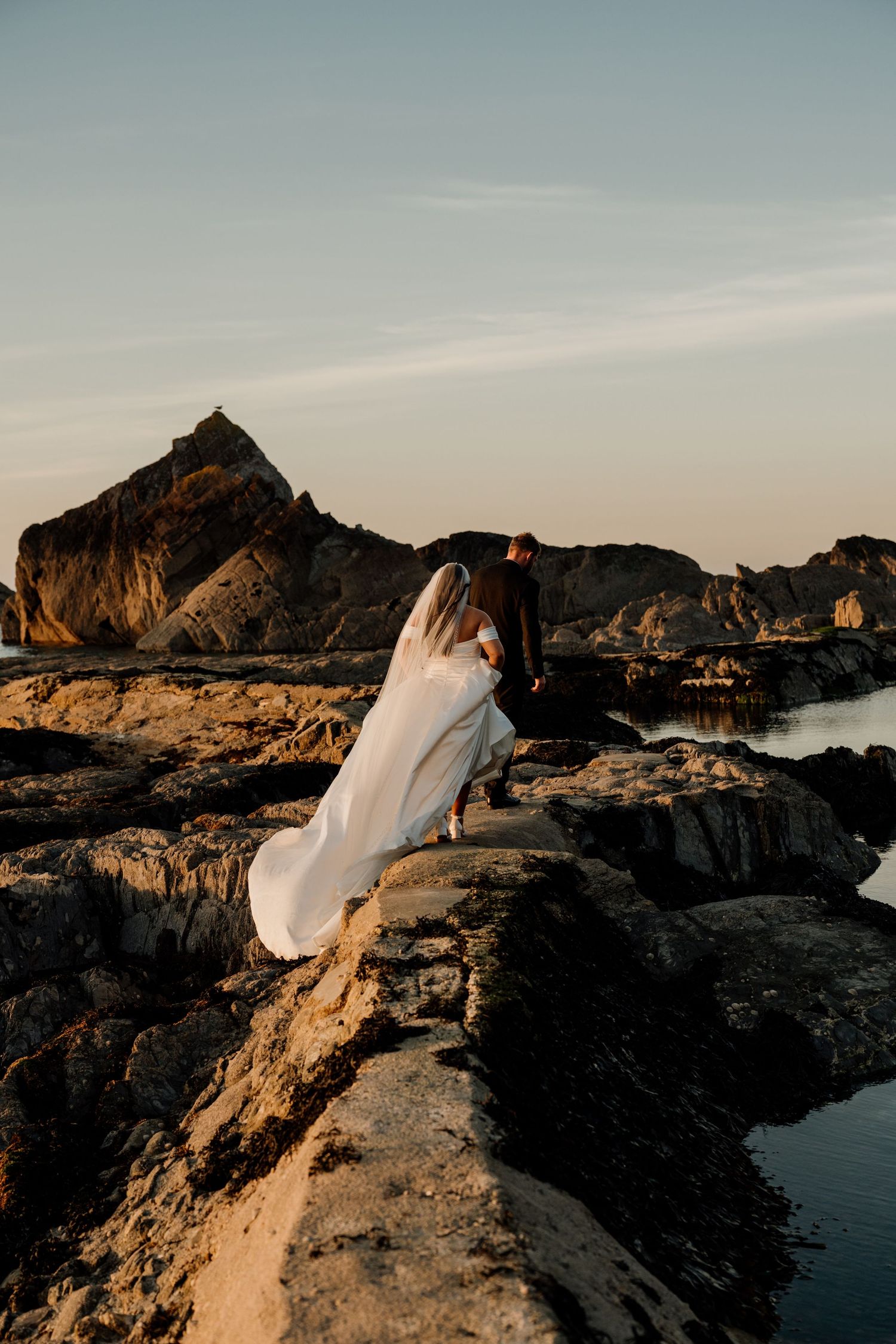 bride and groom walking on the tidal pool at tunnels beaches wedding venue