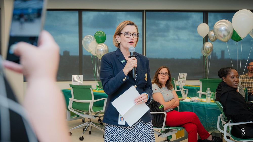 A professional presentation in a meeting room decorated with green and white balloons and office chairs.