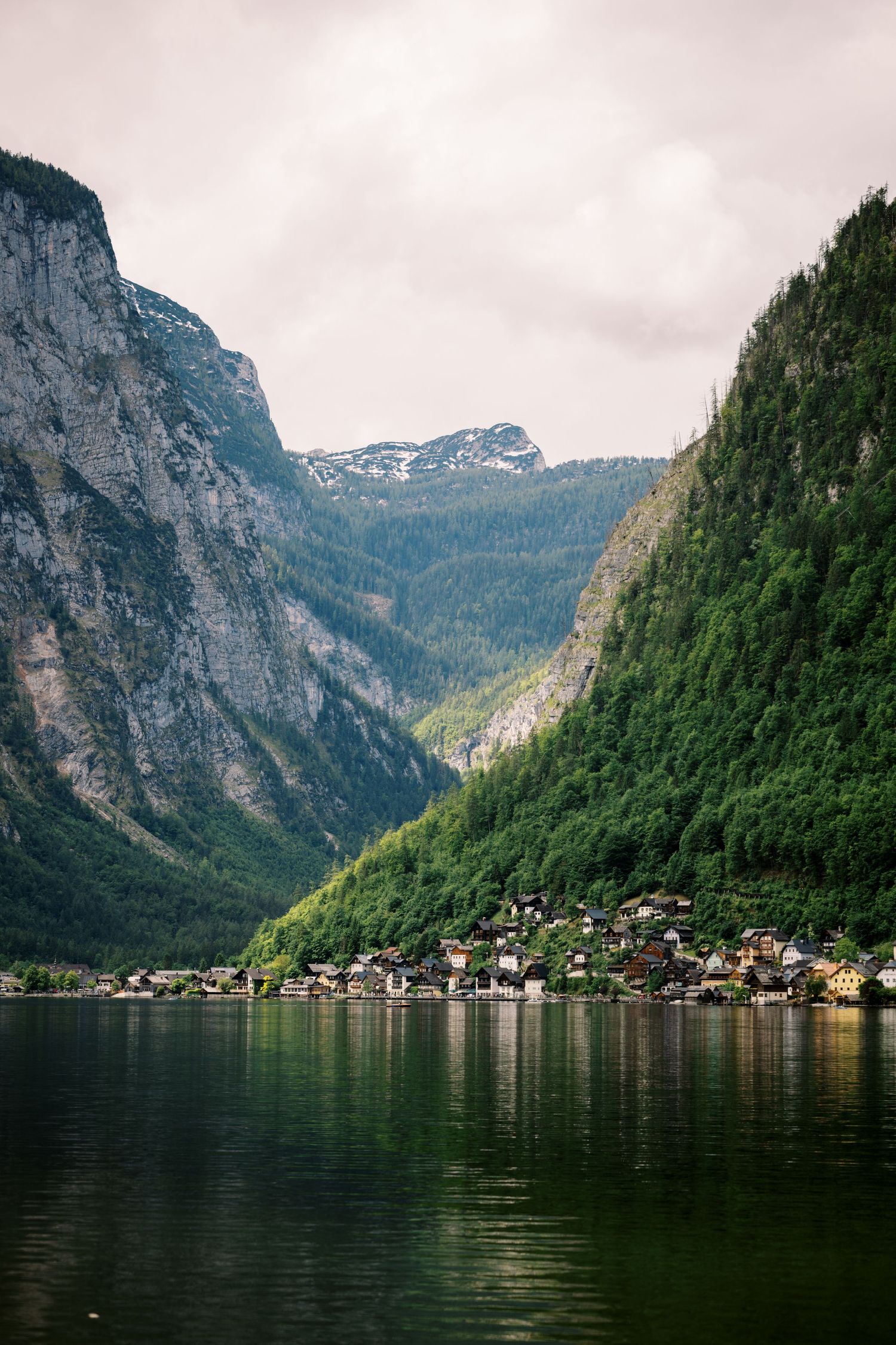 Scenic view of Hallstatt village nestled between mountains and lake in Austrian Alps with reflective waters.
