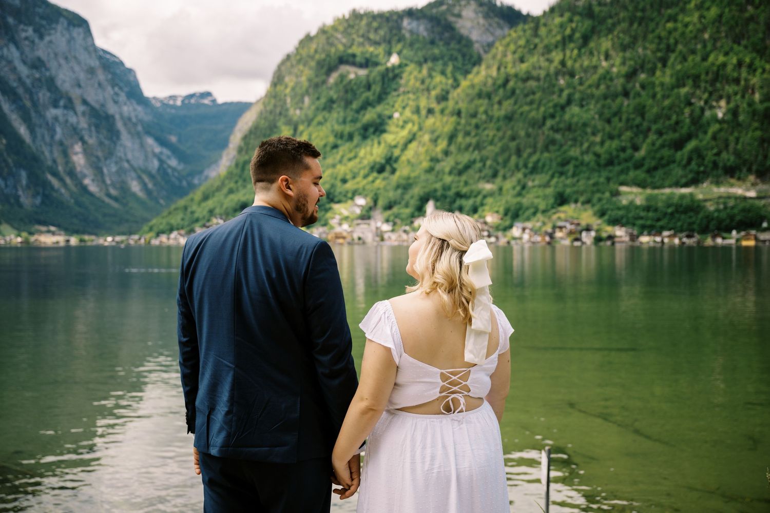 Couple enjoying scenic mountain lake views from waterfront in Hallstatt, Austria.