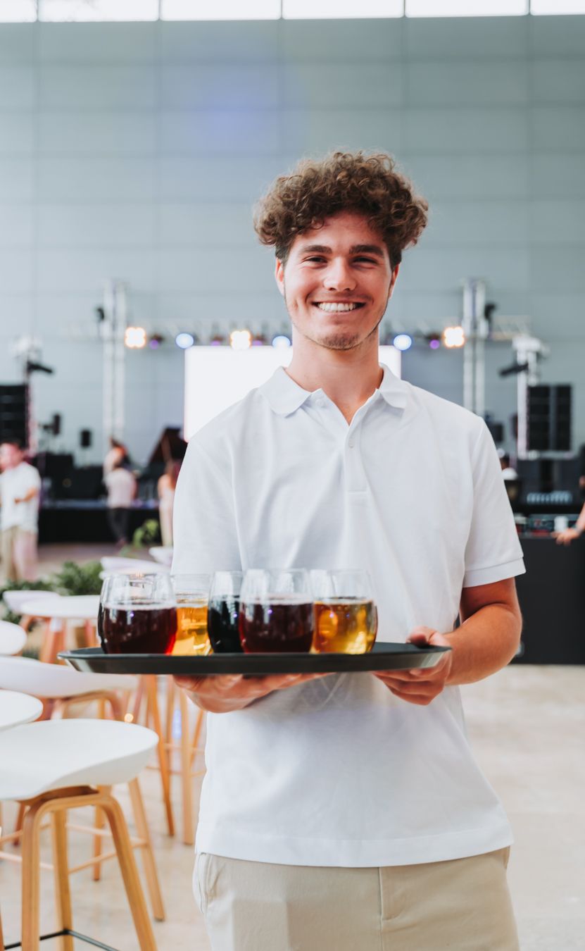 jeune garçon souriant servant des verres sur un plateau