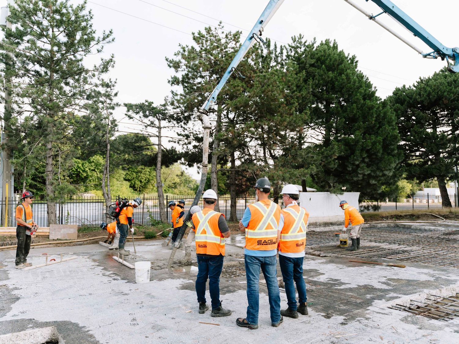 Construction workers in orange safety vests working on an outdoor site.