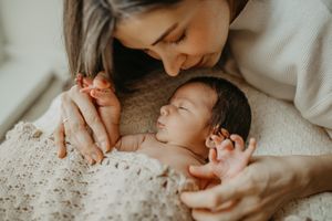Adult and newborn baby laying together on cozy knit blanket in tender intimate moment. bromley and Beckenham newborn photography