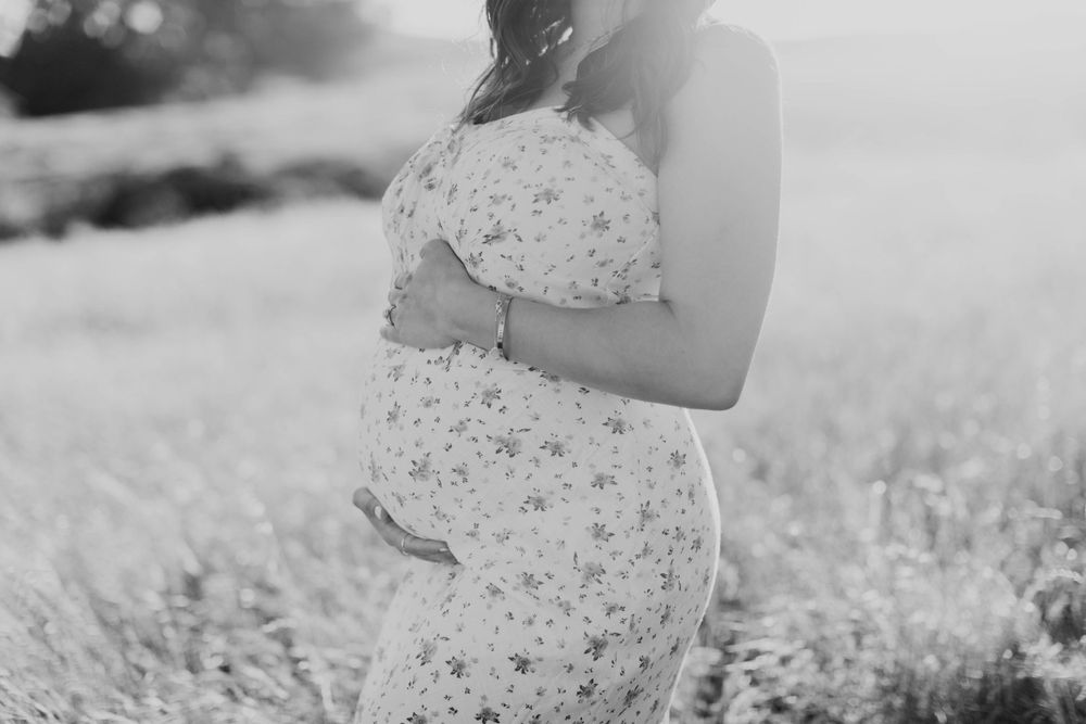 Black and white maternity portraits capture intimate moments in a dreamy outdoor setting.