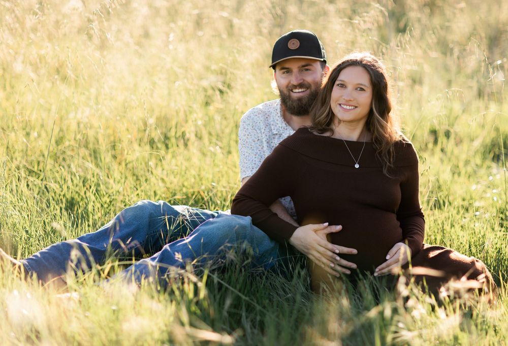 A couple relaxes together in a golden field during sunset creating romantic outdoor portraits.