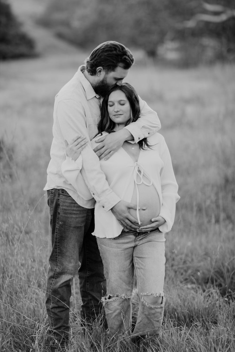 A tender maternity photo sequence shows a couple embracing in a grassy field, captured in black and white.