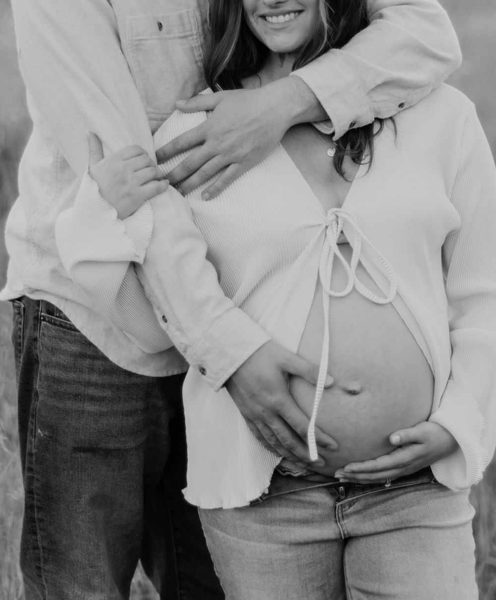 A black and white photo of a couple in denim and white clothing sharing an intimate moment outdoors.