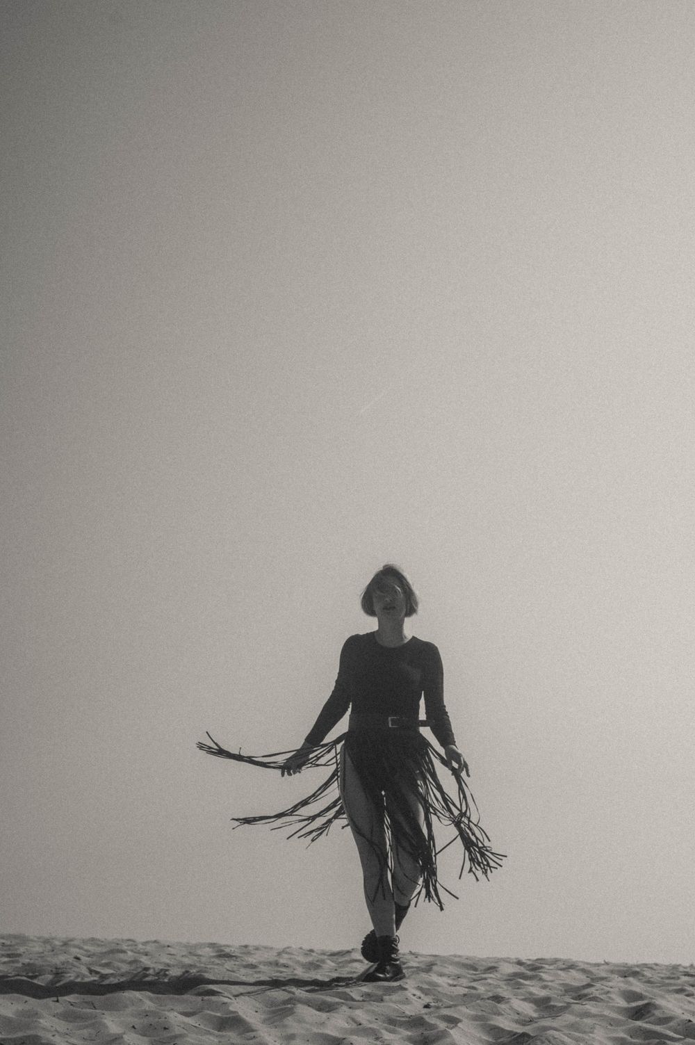 Silhouetted figure stands alone on horizon in minimalist black and white composition.