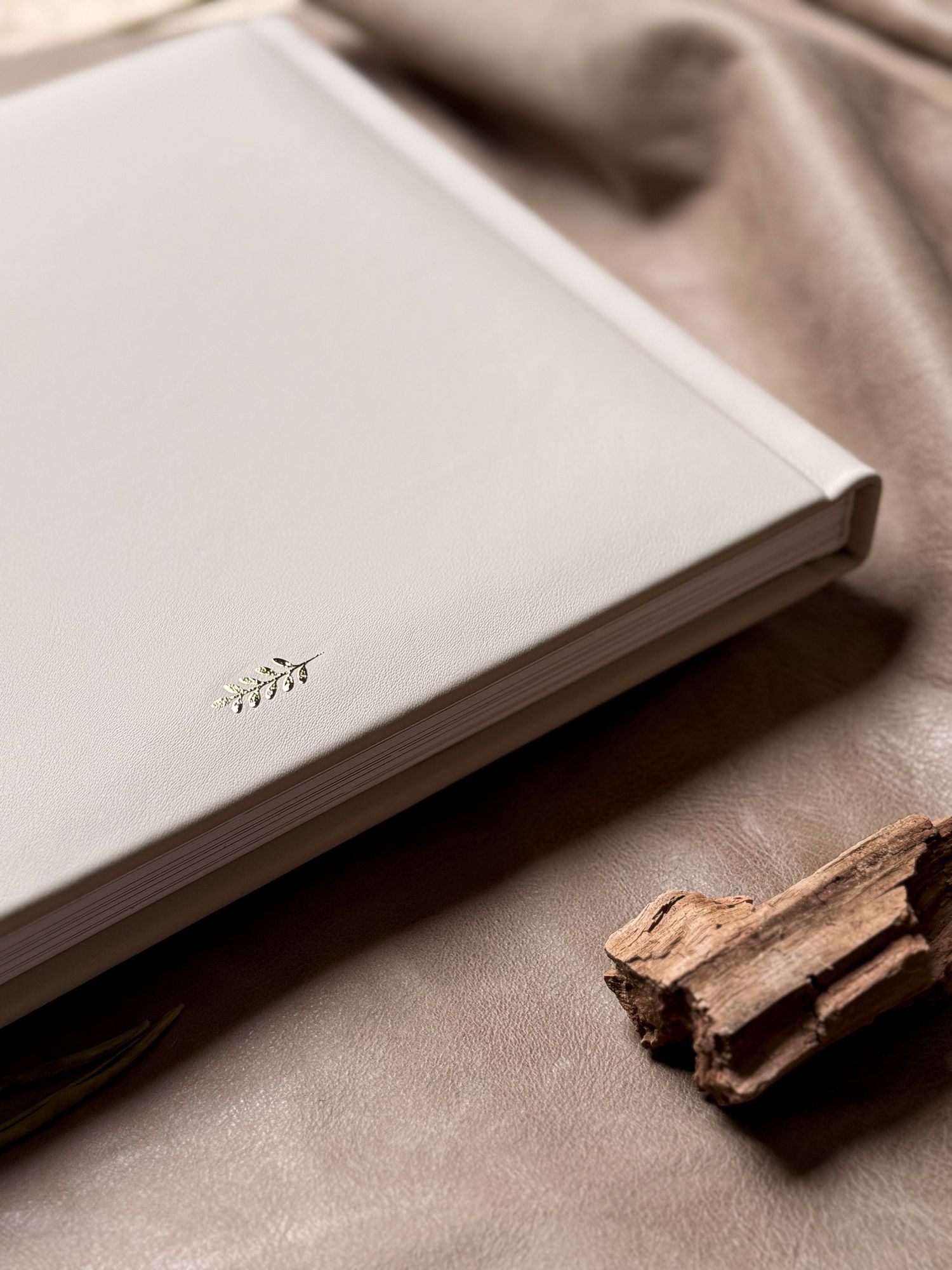 Elegant white photo album with natural wood elements on textured surface.