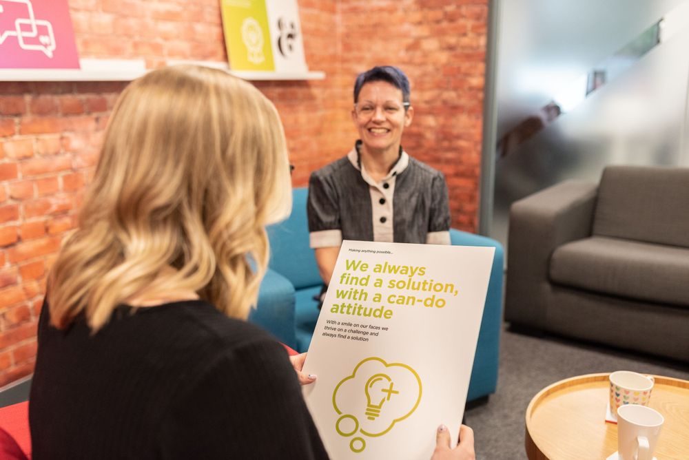 Two people have a business meeting in a brick-walled office space while reviewing presentation materials.