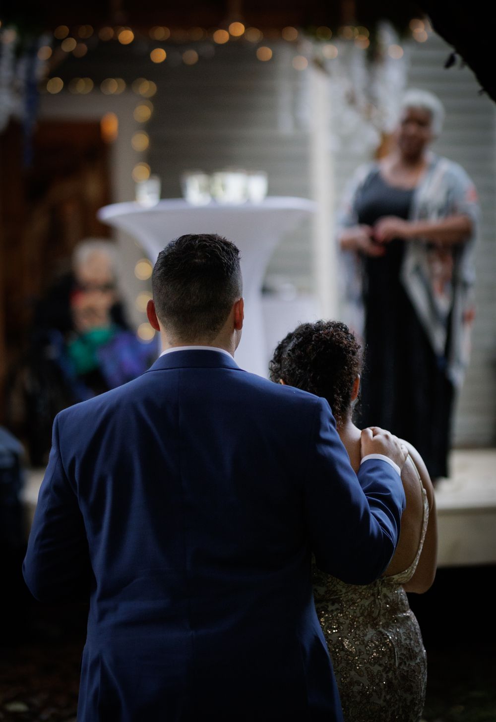 Bride and groom walk hand in hand toward officiant at outdoor ceremony.