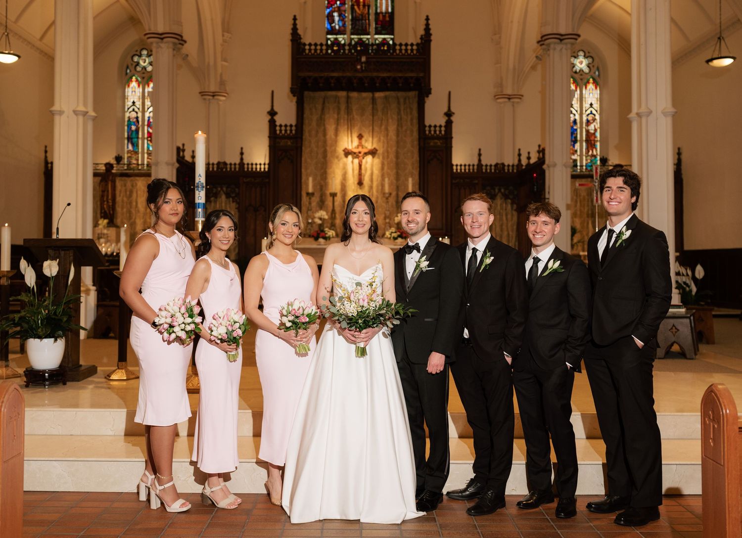 Black and white photo of a wedding ceremony in a traditional church with ornate altar decorations.