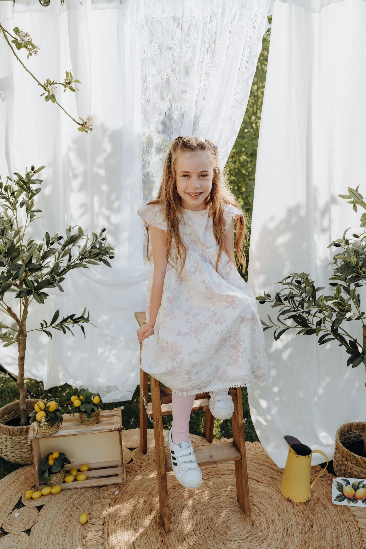 A joyful child stands between expecting parents in a golden sunlit field at sunset.
