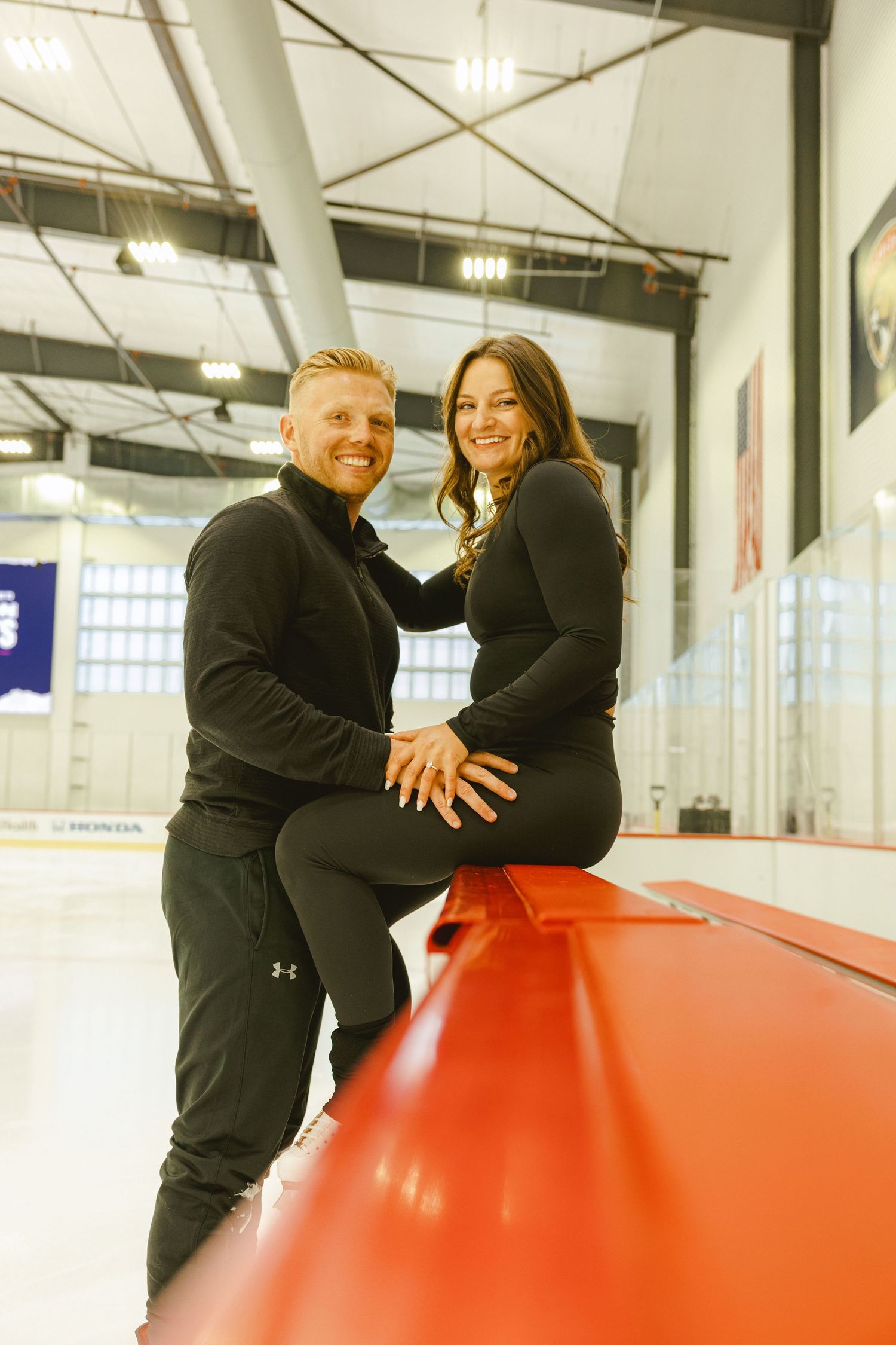 woman sitting on the boards with fiancé standing in front of her for their engagement shoot in south florida