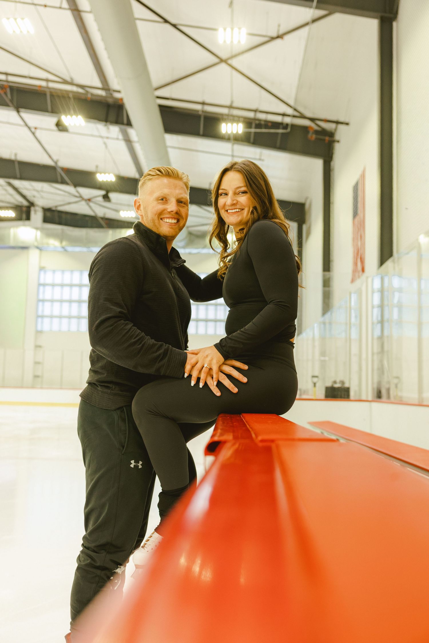 couple sitting on the boards at ice skating rink for their engagement shoot in fort lauderdale