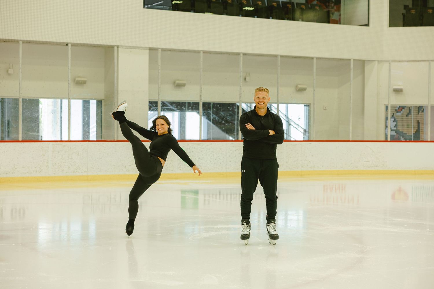 female doing figure skating moves while fiancé watches in ice skating rink for Fort Lauderdale engagement shoot