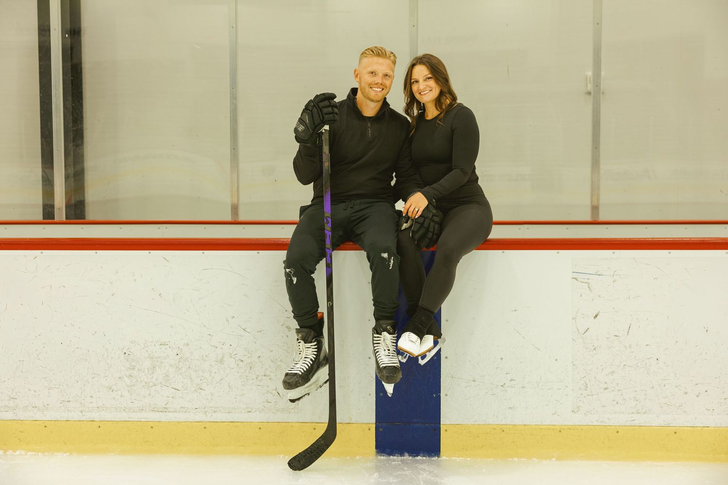 couple sitting on the boards at ice skating rink for their engagement shoot in fort lauderdale